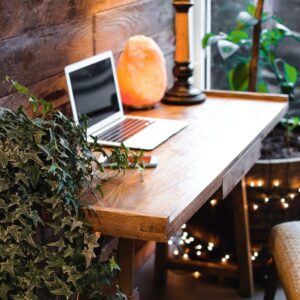 himalayan salt lamp near laptop on wooden table